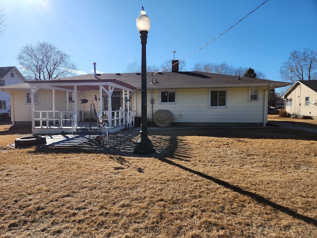 rear view of property featuring a lawn and a chimney