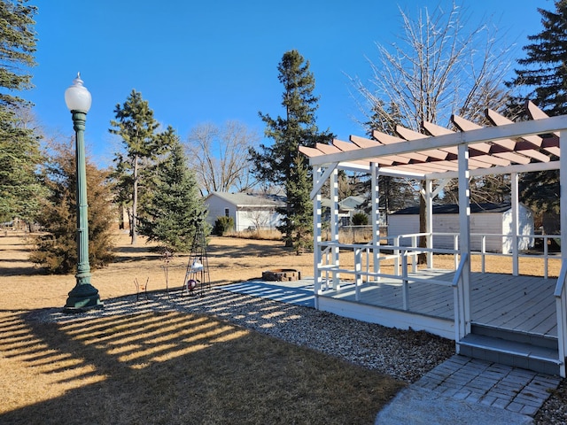 view of yard featuring an outbuilding, a storage unit, a wooden deck, and a pergola