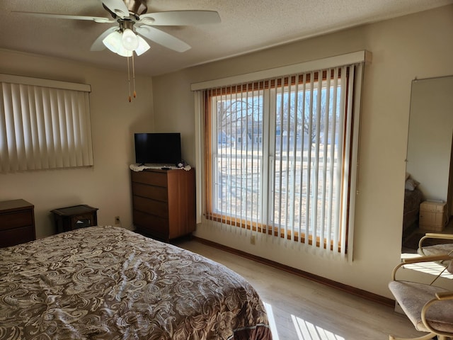 bedroom with a textured ceiling, ceiling fan, wood finished floors, and baseboards