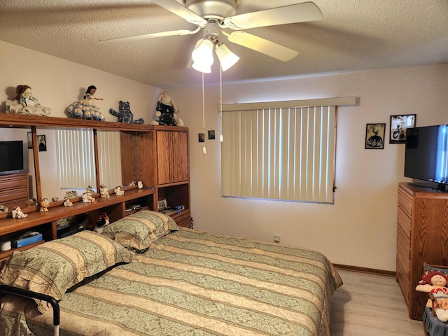 bedroom with light wood finished floors, ceiling fan, baseboards, and a textured ceiling