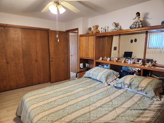 bedroom with a closet, built in study area, ceiling fan, a textured ceiling, and wood finished floors