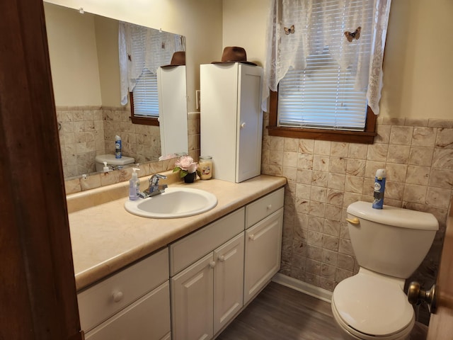 bathroom featuring tile walls, wainscoting, vanity, and toilet