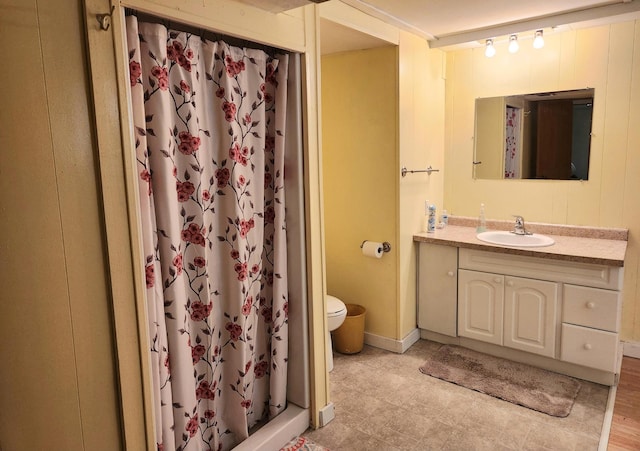 full bathroom featuring a stall shower, baseboards, vanity, and toilet