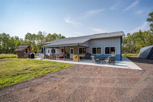 rear view of property with board and batten siding, a patio area, and a yard