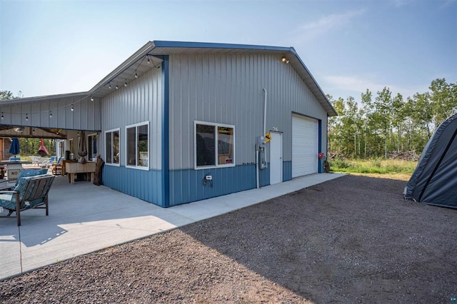 view of side of home featuring driveway, a garage, and a patio