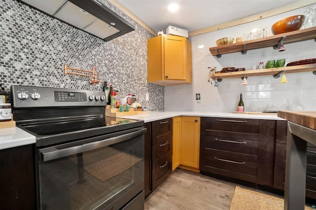 kitchen featuring light wood-style flooring, stainless steel electric range, light countertops, and backsplash