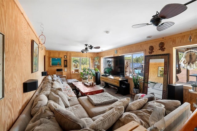 living area with wood walls, ceiling fan, and a wealth of natural light