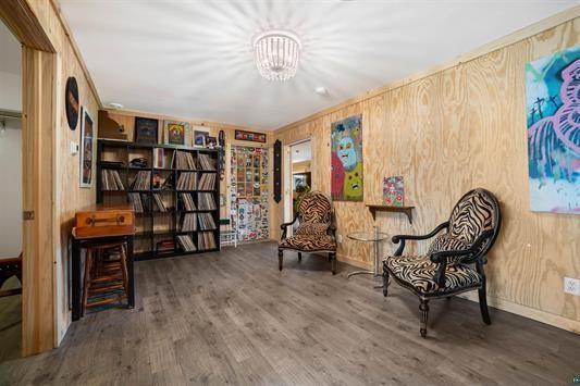 sitting room featuring wood walls, wood finished floors, and an inviting chandelier