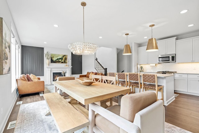 dining area with recessed lighting, visible vents, light wood-style flooring, a high end fireplace, and stairs