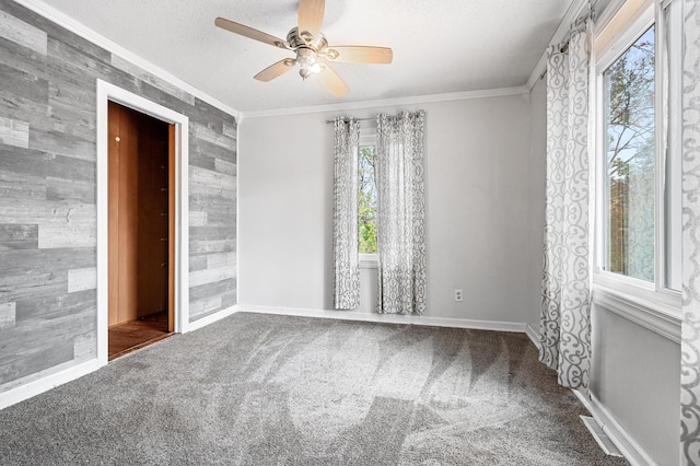 carpeted spare room featuring ceiling fan, a textured ceiling, baseboards, and ornamental molding