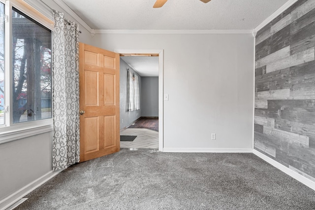 spare room with carpet, crown molding, wooden walls, and a textured ceiling