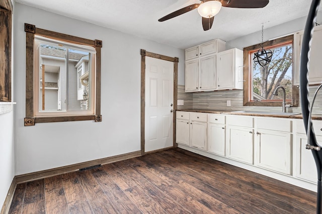 kitchen featuring a ceiling fan, dark wood-style flooring, a sink, decorative backsplash, and white cabinetry