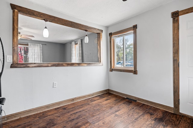 spare room with baseboards, a textured ceiling, wood finished floors, and a ceiling fan