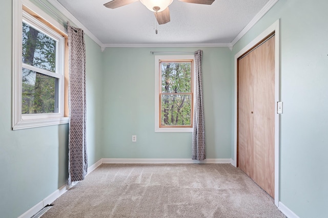 unfurnished bedroom featuring a closet, baseboards, carpet, and crown molding