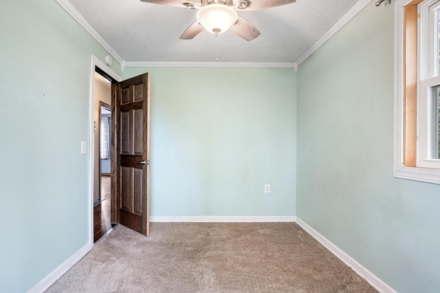 carpeted spare room featuring baseboards, a textured ceiling, ceiling fan, and ornamental molding