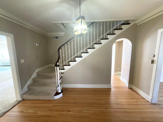 stairs featuring baseboards, wood finished floors, ornamental molding, and radiator heating unit