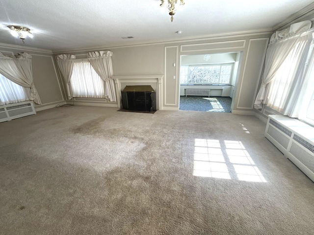 unfurnished living room featuring radiator, crown molding, a fireplace with flush hearth, an AC wall unit, and carpet floors