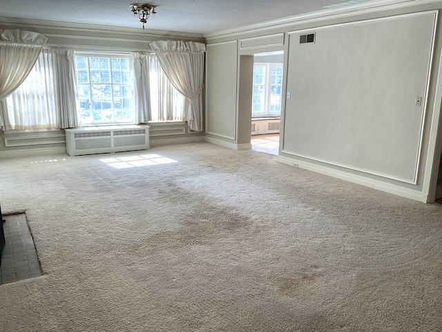 carpeted spare room with visible vents, a textured ceiling, and ornamental molding