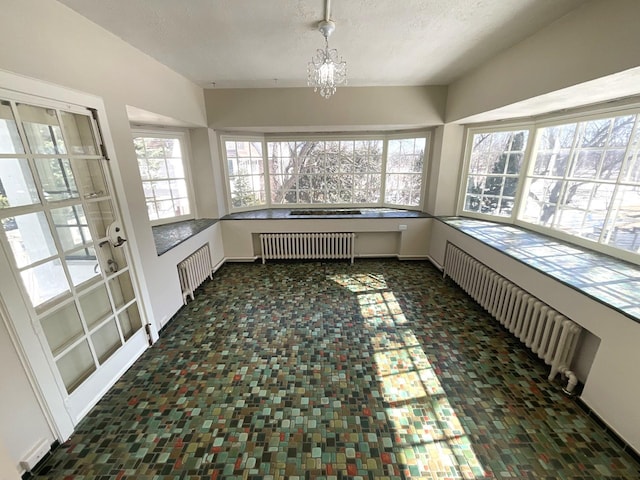 unfurnished sunroom with a notable chandelier and radiator heating unit