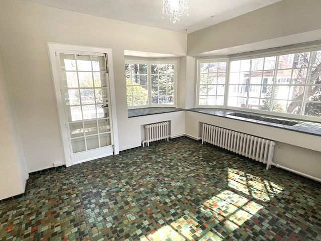 unfurnished sunroom with a notable chandelier and radiator heating unit