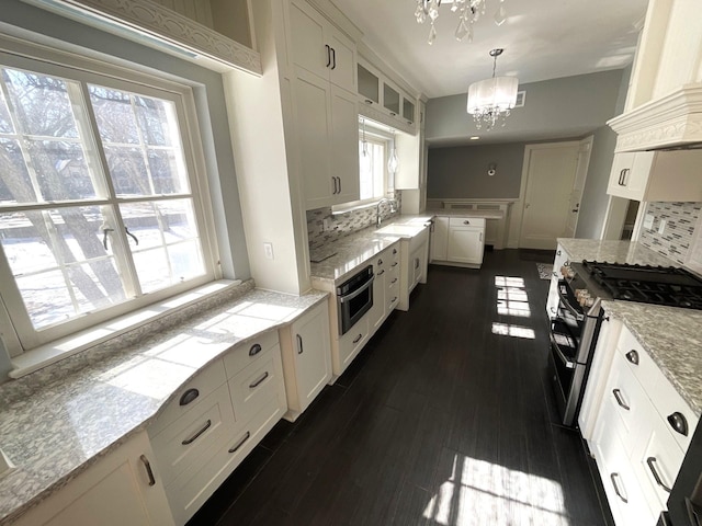 kitchen featuring a sink, white cabinetry, appliances with stainless steel finishes, light stone countertops, and a chandelier