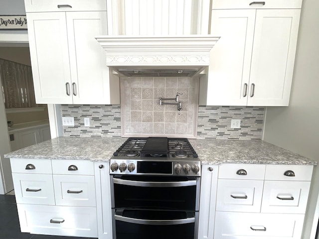 kitchen featuring custom range hood, light stone counters, double oven range, and tasteful backsplash