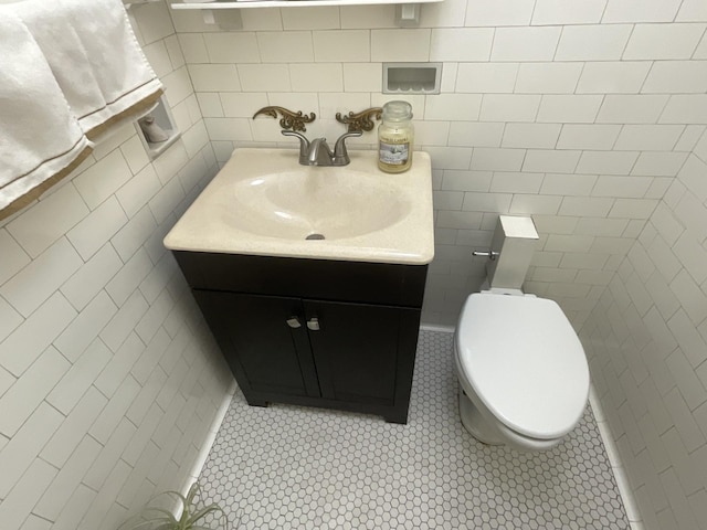 bathroom with tile patterned floors, toilet, tile walls, and vanity