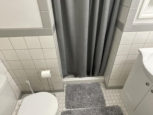 full bathroom featuring tile patterned floors, a shower stall, toilet, and tile walls