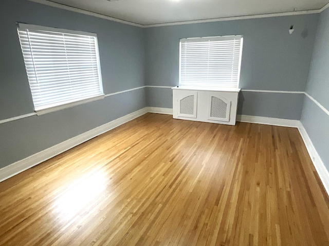 unfurnished room with crown molding, baseboards, and wood finished floors