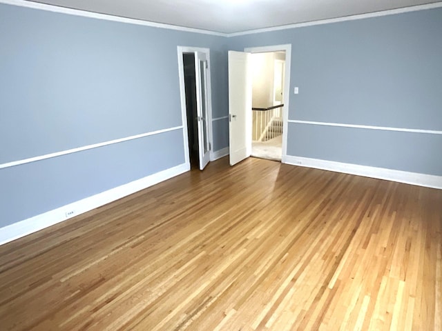 empty room featuring ornamental molding, baseboards, and wood finished floors