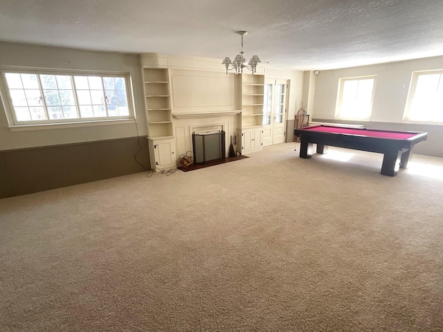 recreation room with pool table, a fireplace with flush hearth, carpet floors, a notable chandelier, and a textured ceiling