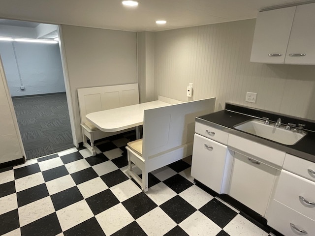 kitchen featuring dark countertops, white cabinets, light floors, and a sink