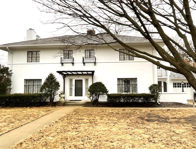 view of front of home with stucco siding and a chimney