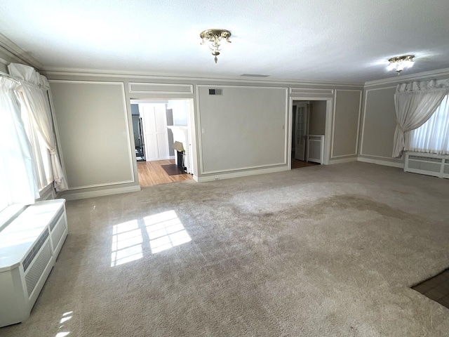 401 5th Ave SW, Austin, MN 55912 - unfurnished living room with a decorative wall, carpet flooring, crown molding, and visible vents