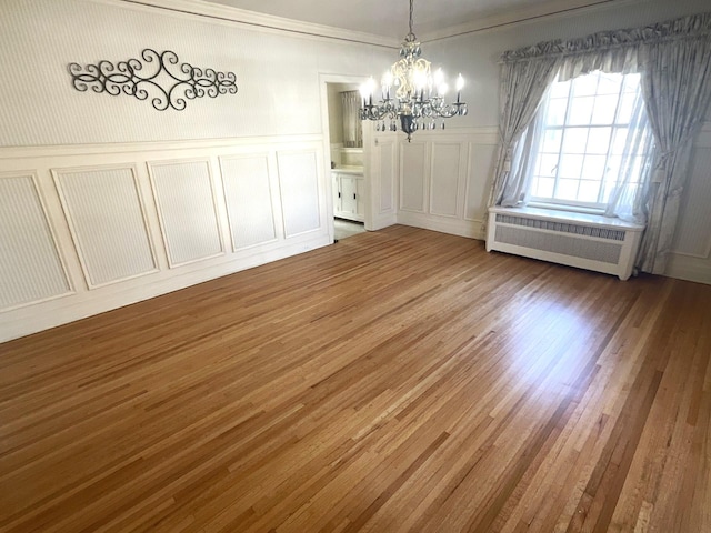 401 5th Ave SW, Austin, MN 55912 - unfurnished dining area with a decorative wall, wood finished floors, wainscoting, an inviting chandelier, and radiator