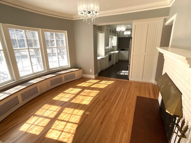 401 5th Ave SW, Austin, MN 55912 - unfurnished dining area with a sink, a notable chandelier, wood finished floors, a fireplace, and ornamental molding