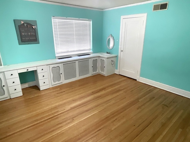 401 5th Ave SW, Austin, MN 55912 - unfurnished office with built in desk, visible vents, ornamental molding, baseboards, and light wood-style flooring