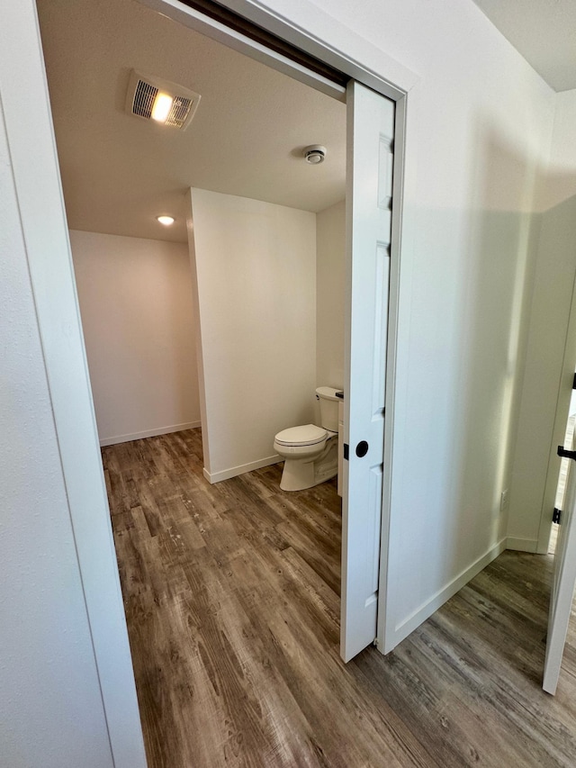 bathroom featuring baseboards, visible vents, toilet, and wood finished floors