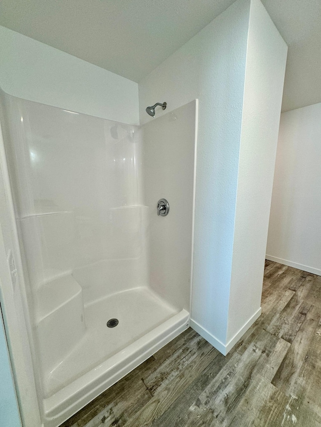 bathroom featuring baseboards, a shower, and wood finished floors