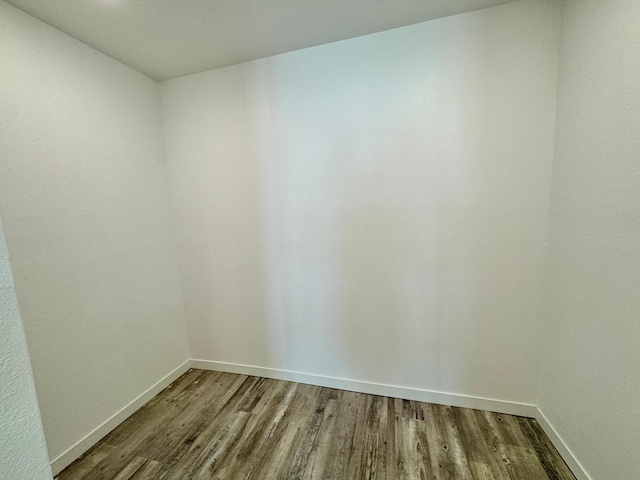 spare room with baseboards and wood finished floors