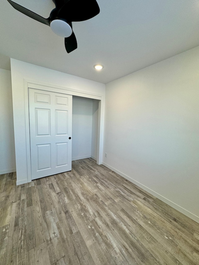 unfurnished bedroom with baseboards, ceiling fan, wood finished floors, a closet, and recessed lighting