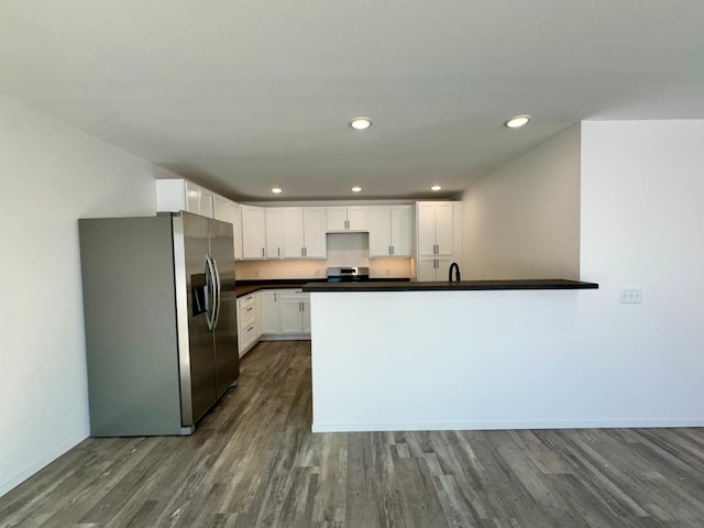 kitchen with stainless steel appliances, dark countertops, dark wood-style flooring, and white cabinetry