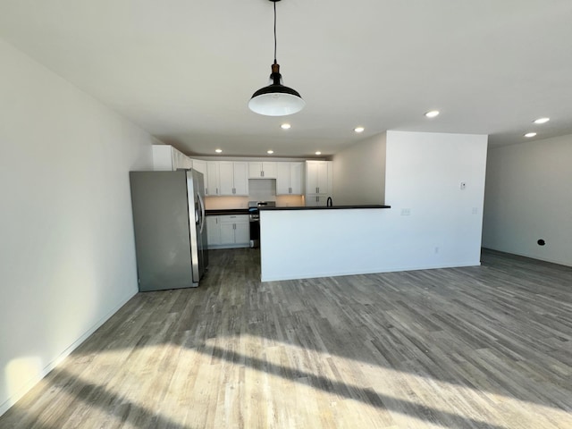 kitchen featuring appliances with stainless steel finishes, dark countertops, white cabinets, and wood finished floors