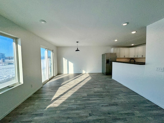 unfurnished living room featuring a textured ceiling, dark wood-style flooring, a sink, and recessed lighting