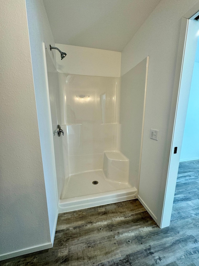 bathroom featuring baseboards, a shower, and wood finished floors