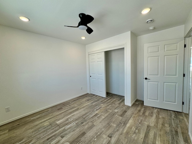 unfurnished bedroom featuring a closet, recessed lighting, wood finished floors, and baseboards