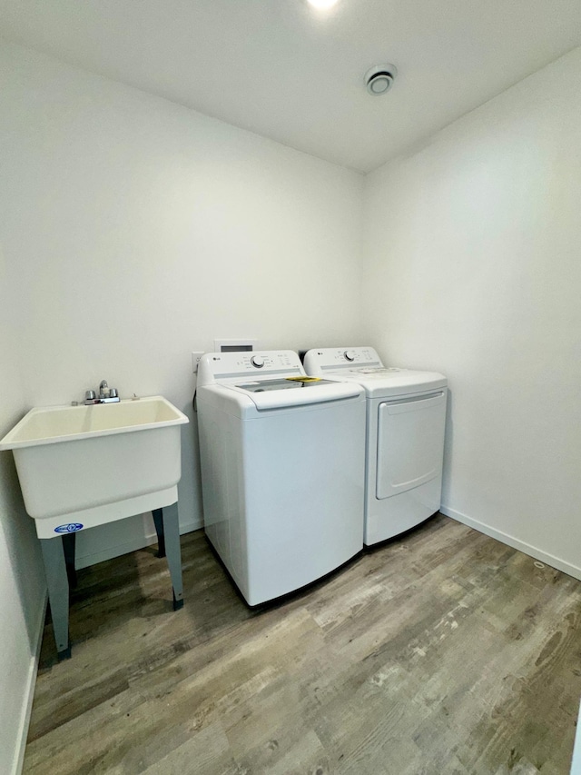 laundry room featuring laundry area, a sink, light wood finished floors, and separate washer and dryer