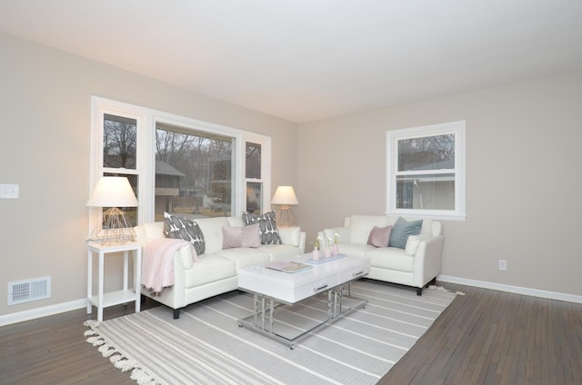 living area featuring wood-type flooring, visible vents, and baseboards