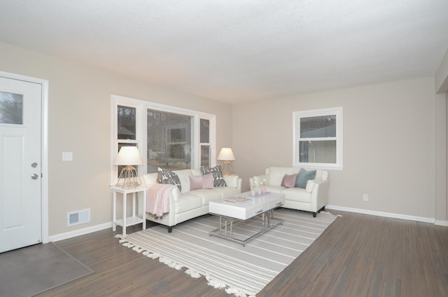 living area featuring visible vents, baseboards, and wood finished floors