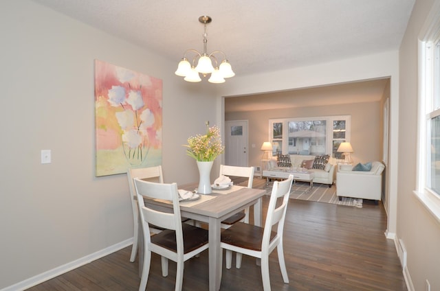 dining space with dark wood-style floors, baseboards, and a chandelier